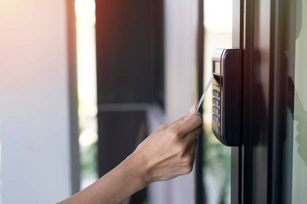 young woman using RFID tag key card, fingerprint and access control to open the door in a office building stock photo