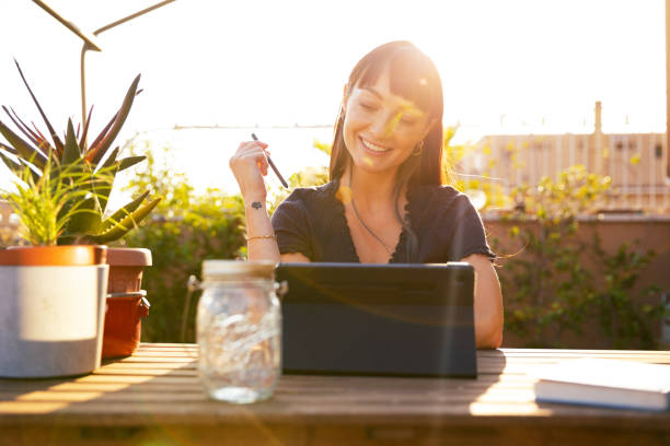 Young woman using tablet on terrace at sunset stock photo