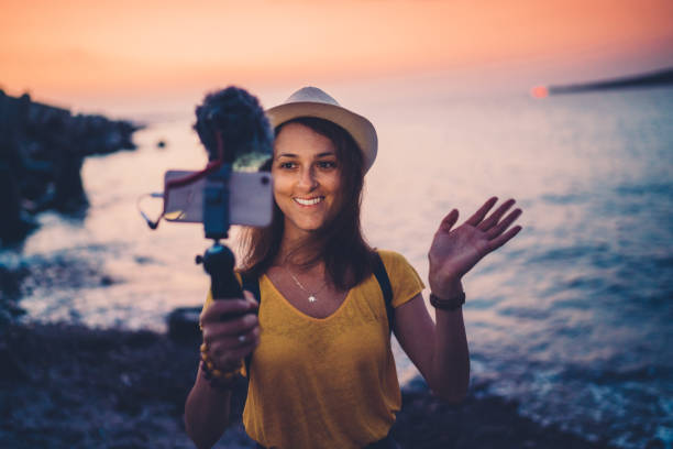 Young woman vlogging from beach holiday Young influencer vlogging from the seaside at sunset Travel Blogger stock pictures, royalty-free photos & images