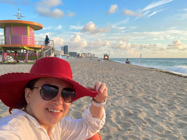 Young woman waering red hat taking a selfie at South Beach, Miami, USA stock photo