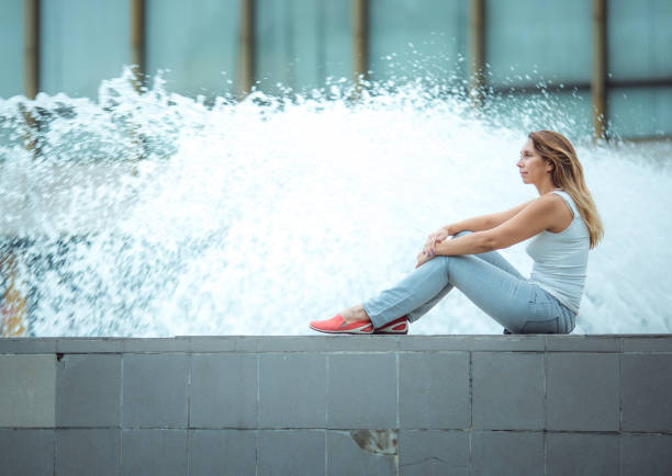 Young woman walking around the city near the fountains. Successful businesswoman enjoys the sound of water stock photo