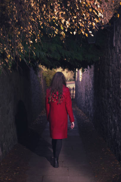 Young woman walking down a dark alley stock photo