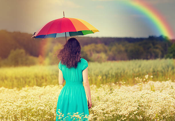a young woman walking in a corn field underneath a rainbow - rain woman sun stockfoto's en -beelden