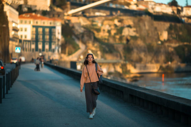a young woman walks along the city's river embankment. - people portugal imagens e fotografias de stock