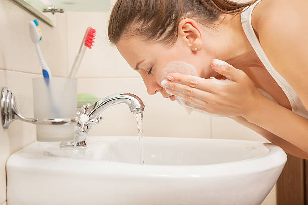 young woman washing face stock photo