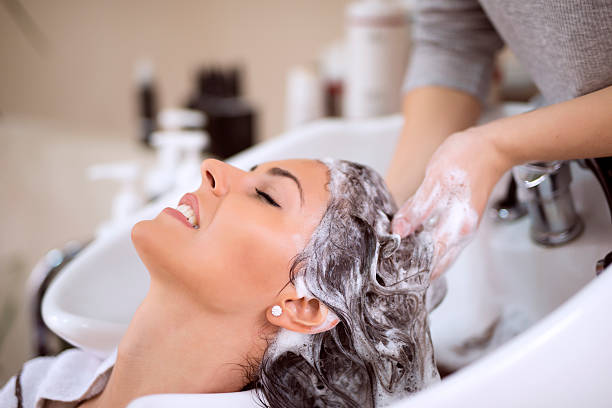 young woman washing hair in salon - woman washing hair stockfoto's en -beelden
