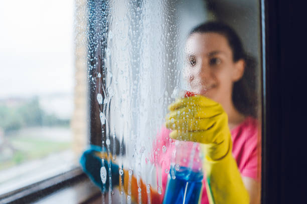 Young woman washing window Young woman wiping windows at home cleaner stock pictures, royalty-free photos & images