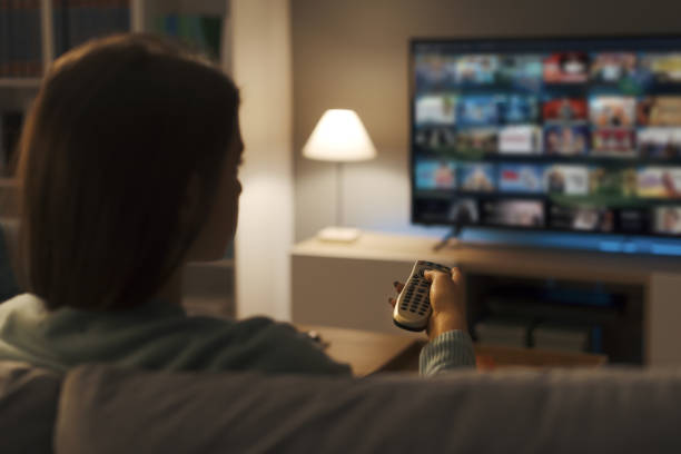 Young woman watching video on demand on her TV stock photo