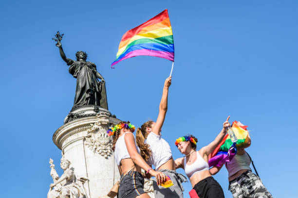 une jeune femme agite un drapeau arc-en-ciel haut pendant le défilé de fierté gaie à paris, france. - marche des fiertés photos et images de collection