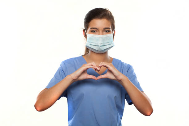 Young Woman Wearing Medical Scrubs and a Surgical Mask vertical photograph of a Young Woman Wearing Medical Scrubs and a Surgical Mask female nurse stock pictures, royalty-free photos & images