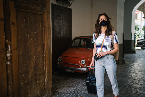 She looks for directions on cellphone, while walking past an old Fiat 500