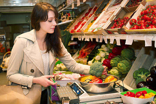 Young woman who weighs vegetables that it is buying stock photo