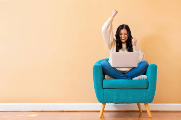 Young woman with a laptop computer with successful pose Young woman with a laptop computer with successful pose sitting in a chair exhilaration stock pictures, royalty-free photos & images