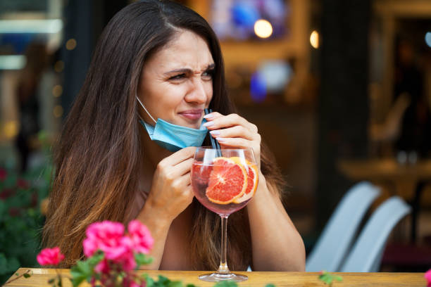 Young woman with a protective face mask drinking a cocktail stock photo