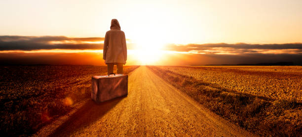 Young woman with a suitcase at sunset stock photo