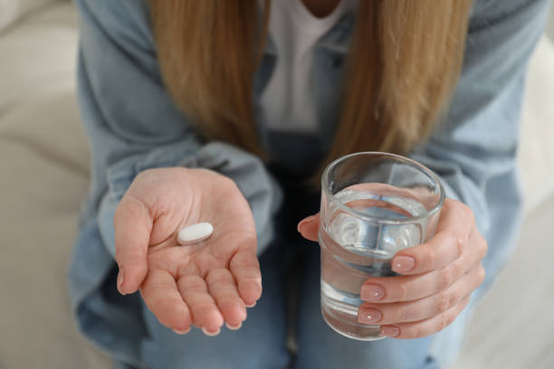 Young woman with abortion pill and glass of water on blurred background, closeup Young woman with abortion pill and glass of water on blurred background, closeup abortion pill stock pictures, royalty-free photos & images
