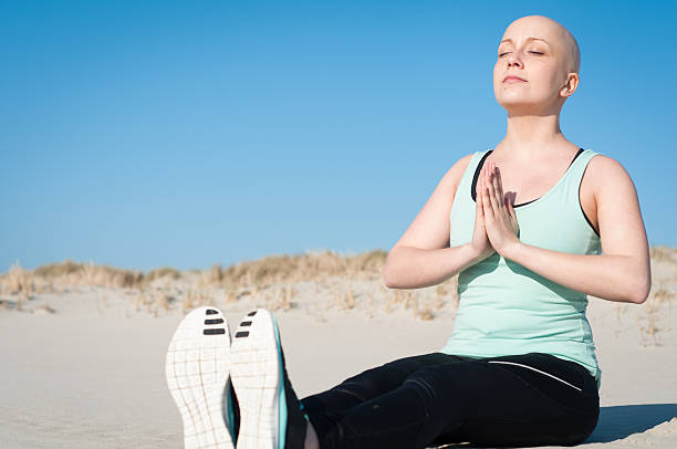 jovem mulher com bald head fazer yoga depois de resistir a quimioterapia - bald beach imagens e fotografias de stock