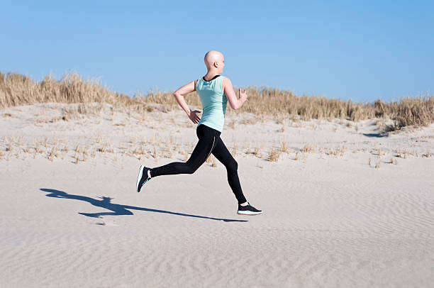 jovem mulher com bald head jogging após quimioterapia - bald beach imagens e fotografias de stock