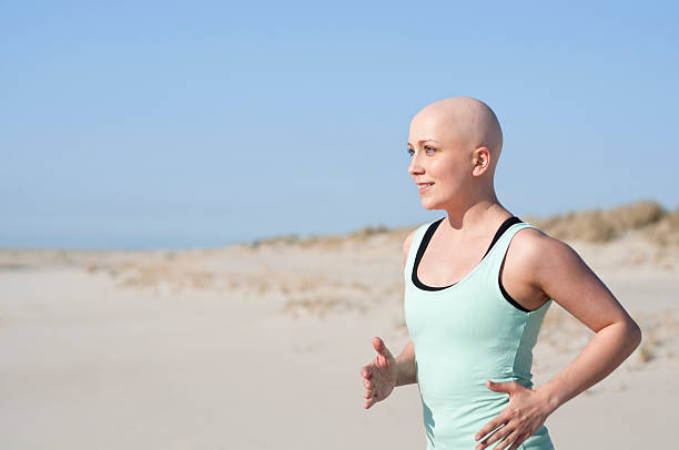 jovem mulher com bald head jogging após quimioterapia - bald beach imagens e fotografias de stock