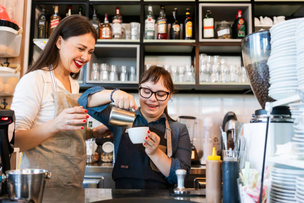 Young woman with Down Syndrome working at cafe preparing coffee stock photo