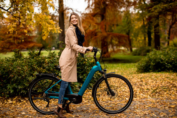 Young woman with electric bicycle in te autumn park stock photo
