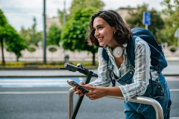 jonge vrouw met elektrische scooter op de straat gebruikend slimme telefoon - elektrische step stockfoto's en -beelden