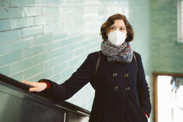 Young woman with FFP2 mask on an escalator stock photo