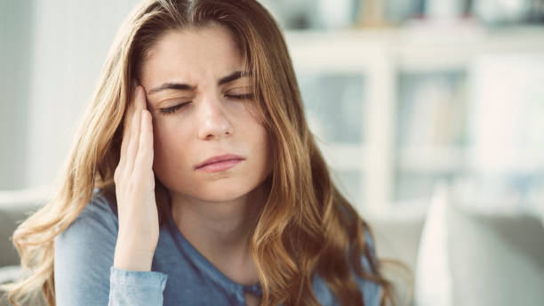 young woman with headache in home interior - migraine imagens e fotografias de stock