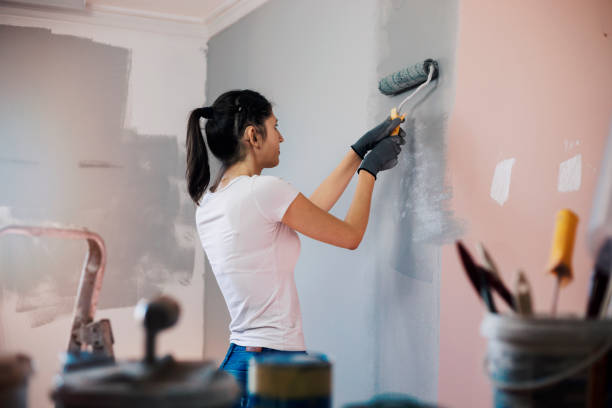 Young woman with hearing aid painting walls Young woman with hearing aid, during reconstruction of apartment, enjoying while painting her walls diy stock pictures, royalty-free photos & images
