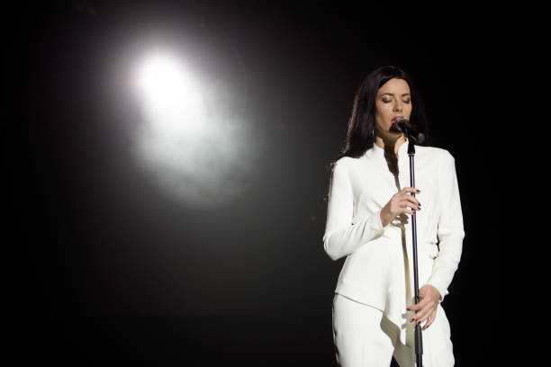 Young woman with microphone and white lights on a concert stock photo
