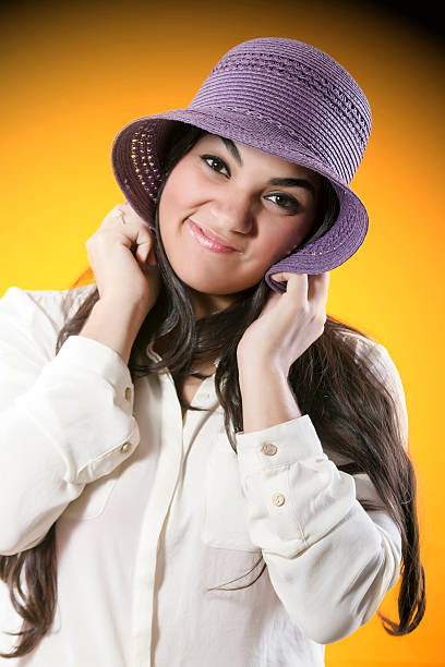 Young woman with purple hat and beautiful face expressing shynes stock photo