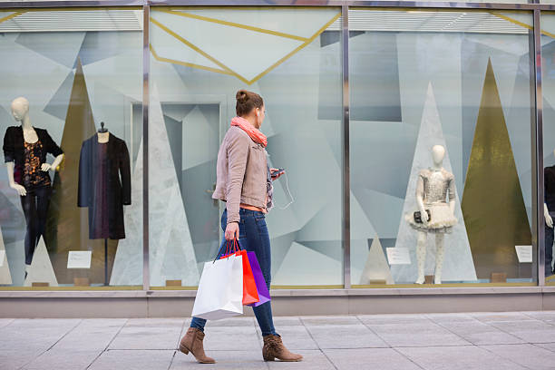 young woman with shopping bags looking at window display - etalages kijken stockfoto's en -beelden