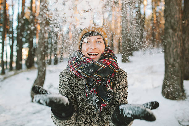 Young woman  with snow in hands in winter forest stock photo