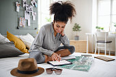 istock Young woman with tablet and map indoors at home, planning traveling trip. 1300843633