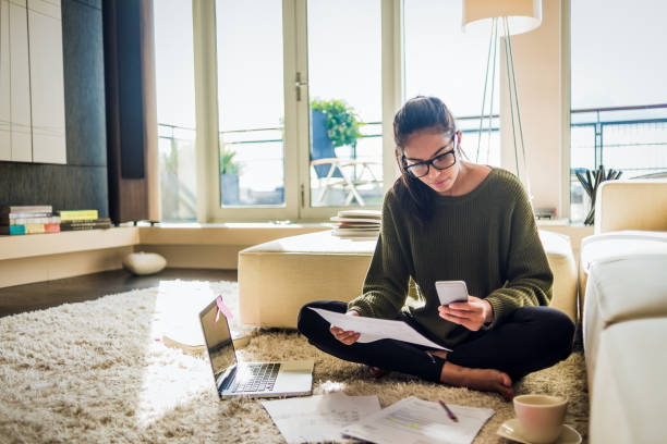 young woman working from home young woman sitting on the floor of her living room and working intelligence photos stock pictures, royalty-free photos & images