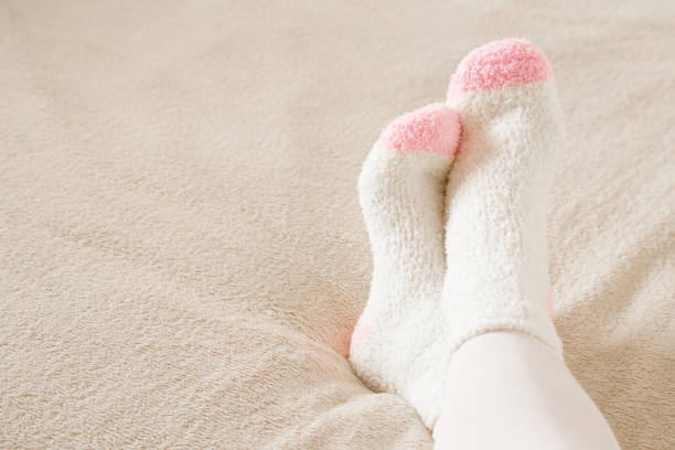 Young woman's legs in white warm socks lying on beige blanket in bed. Closeup. Empty place for text, quote or sayings.  fluffy stock pictures, royalty-free photos & images