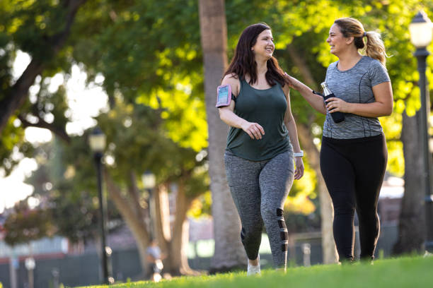 jonge vrouwen joggen en gezond te krijgen in het park - wandelen lichaamsbeweging stockfoto's en -beelden