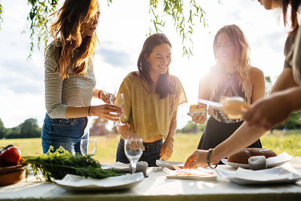young women preparing a table for an outdoor dinner party - sunset dining stockfoto's en -beelden