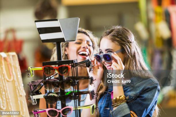 Young women shopping at the mall, trying on sunglasses