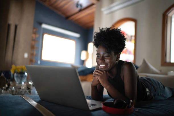 jonge vrouwen kijken naar film op een laptop thuis - kijken naar stockfoto's en -beelden