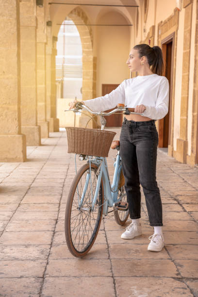 young women with bicycle looking away in a small town stock photo