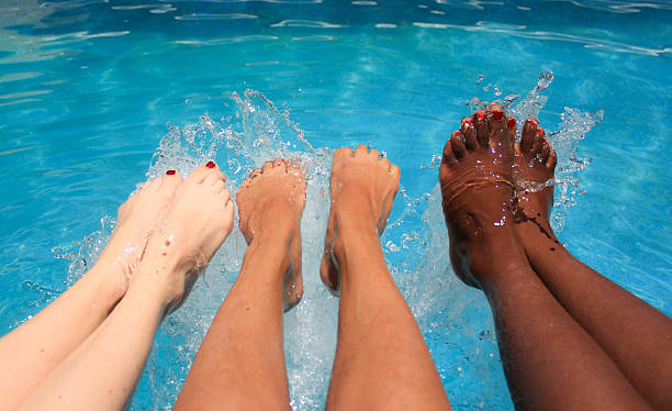 Young women's legs splashing water in a swimming pool stock photo