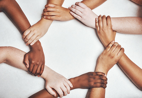 Shot of a group of hands holding on to each other against a white background