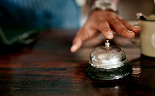 Closeup shot of an unrecognisable man ringing a service bell in a cafe