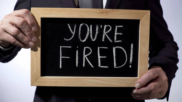 Youre fired with exclamation written on blackboard, businessman holding sign stock photo
