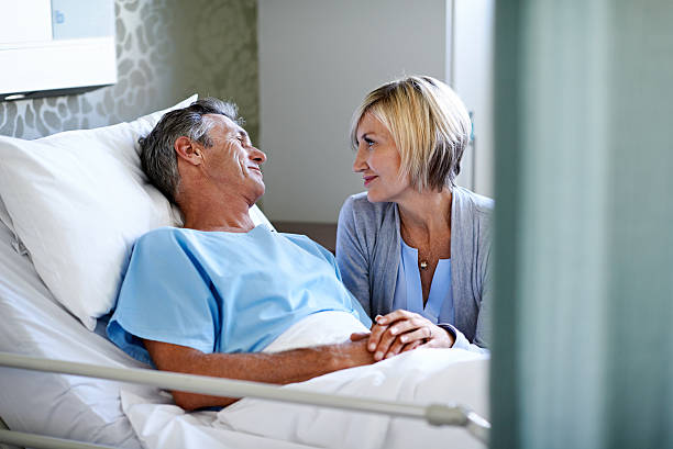 You're looking so much better today Shot of a wife comforting her husband lying in a hospital bed patient in hospital bed stock pictures, royalty-free photos & images