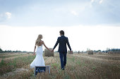 Married couple taking a walk on a field of hay bales, leaving back a mini blackboard that is written the word “love”.