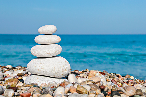 Zen stones stacked at beach against a blue sky and sea with copy space