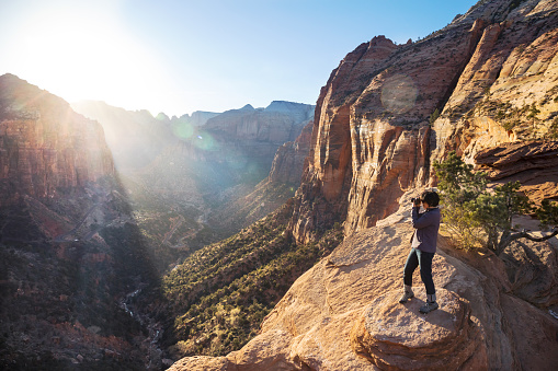mature woman taking a picture of the sunset at lookout point in Zion National Park