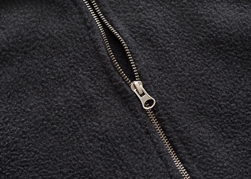 Closeup of a zipper on a black fleece coat.